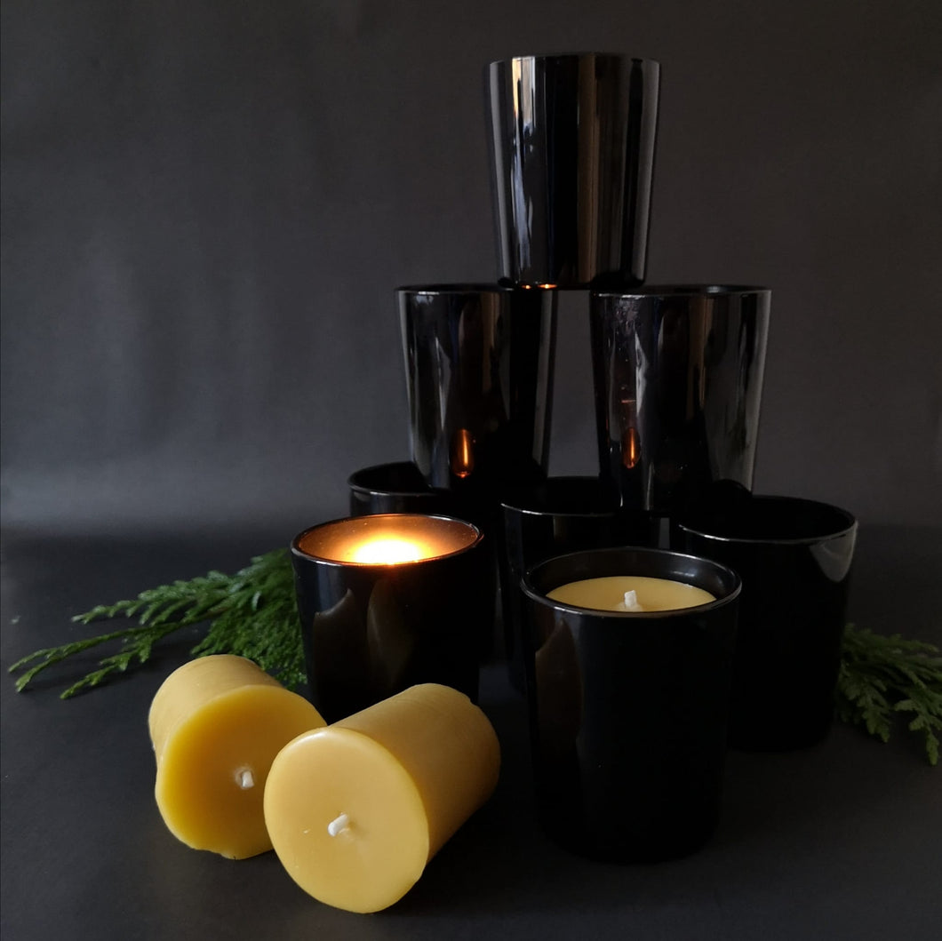 Black glass votive holders with Gold Rustic Votives. One is lit.