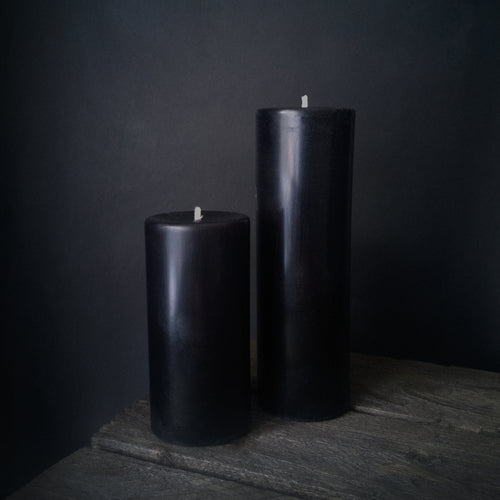 A small and medium Rustic Beeswax Pillar Black candles on a wooden box