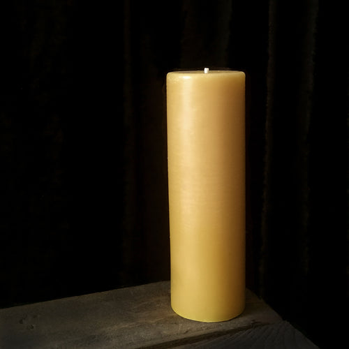 A gold Beeswax Pillar Candle on a wooden box